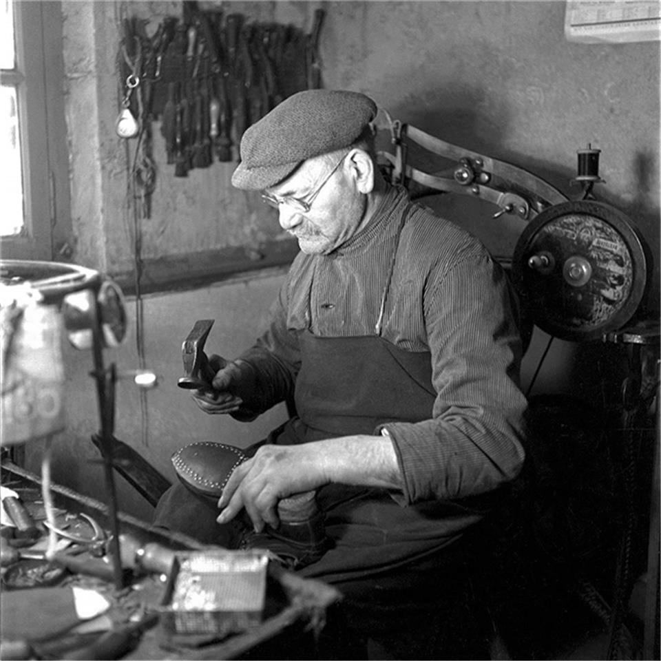 Schuhmacher Overhage beim Beschlagen einer Schuhsohle (1938).