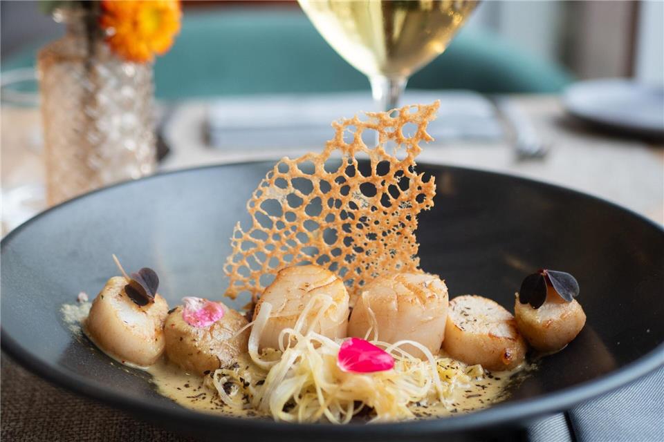 Sechs Nüsse in einer Reihe auf Lauch- und Quinoabett: So richtet Küchenchef Aurelien Leclerc seine Jakobsmuscheln an. Dazu empfiehlt er einen trockenen Weißwein.Andreas Drouve/dpa-tmn