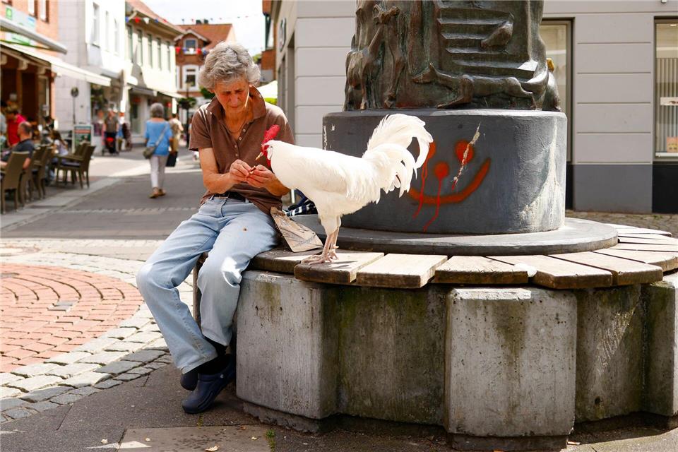 Sibylle Radtke füttert ihren Hahn Willi in der Innenstadt.Frank Molter/dpa