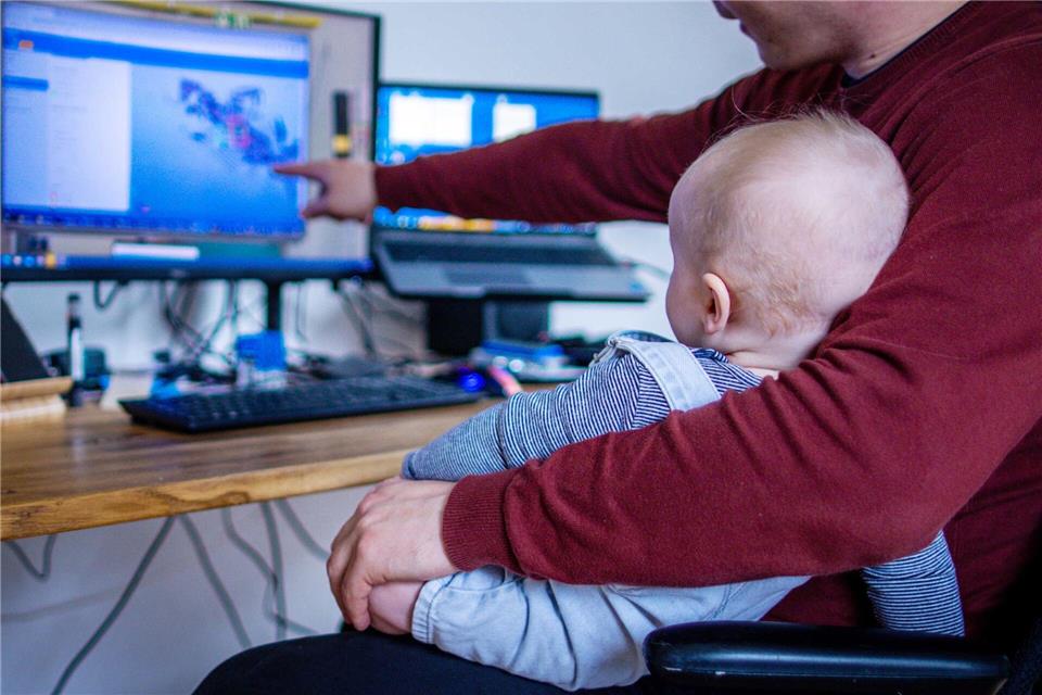 Sicher nicht ganz einfach: Ein junger Vater arbeitet im Homeoffice mit seinem Sohn. (Symbolbild)Jens Büttner/dpa