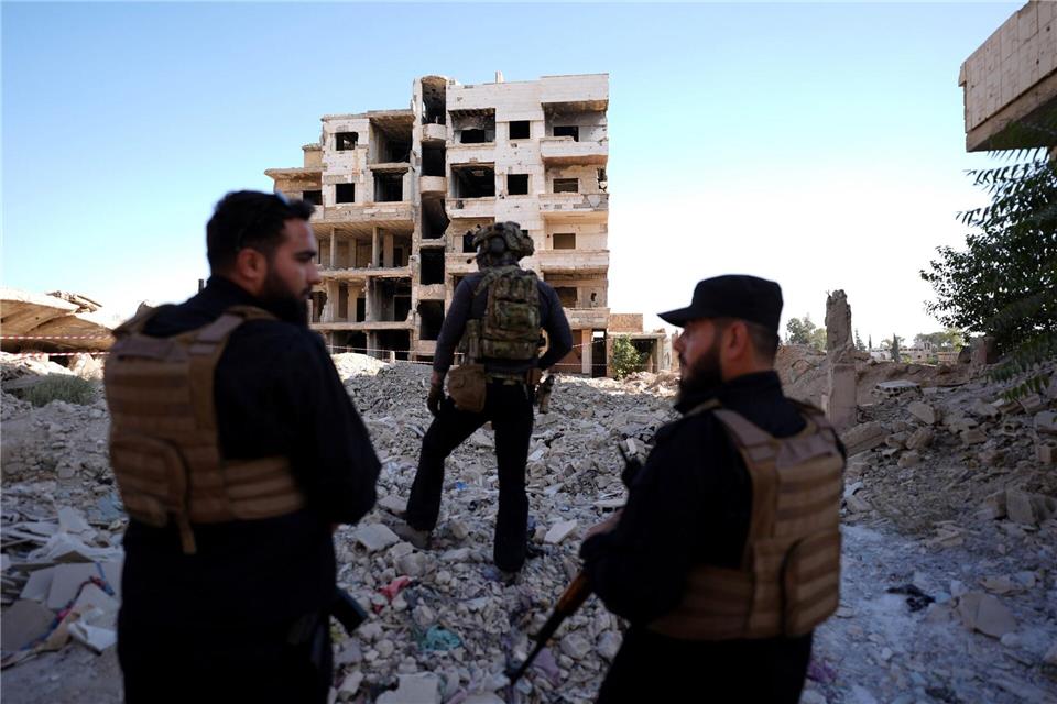 Sicherheitskräfte aus Syrien und aus Deutschland sichern den Besuch von Außenminister Wadephul bei einem humanitären Projekt in einer Straße mit während des Bürgerkriegs zerbombten Häusern in Harasta ab. Marcus Brandt/dpa