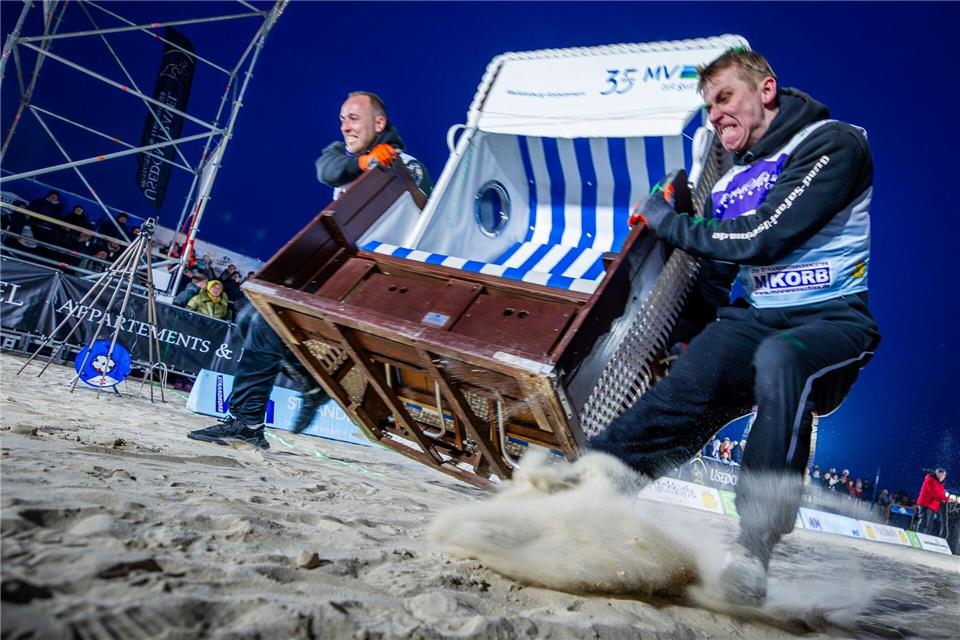 Sie geben alles: Das Team „Quad Safari Usedom“ mit Phillip Schmidt (l) und Finley Liemen (r) gewinnt den Finallauf bei der 18. Strandkorb Weltmeisterschaft auf der Insel Usedom mit einer neuen Weltrekordzeit von 4,56 Sekunden. Die Zweierteams müssen bei dem Wettkampf einen etwa 60 Kilogramm schweren Strandkorb über die 20 Meter lange Strecke über den Ostseestrand ins Ziel schleppen.Jens Büttner/dpa