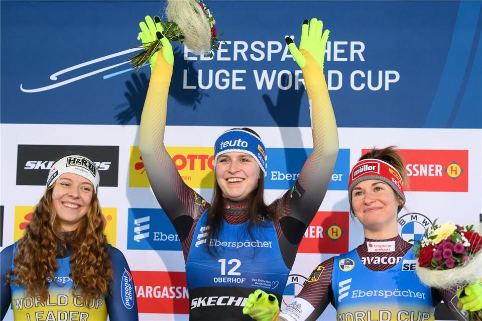 Siegerin Merle Fräbel (Deutschland, M), die Zweitplatzierte Lisa Schulte (Österreich, l) und die Drittplatzierte Julia Taubitz (Deutschland) stehen in Oberhof auf dem Podium.Robert Michael/dpa