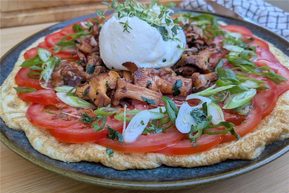 Sieht auf den ersten Blick aus wie eine Pizza, ist aber ein Omelett: Der Eierfladen wird mit Tomatenscheiben, gebratenen Pfifferlingen und Burrata belegt. Doreen Hassek/hauptstadtkueche.blogspot.com/dpa-tmn