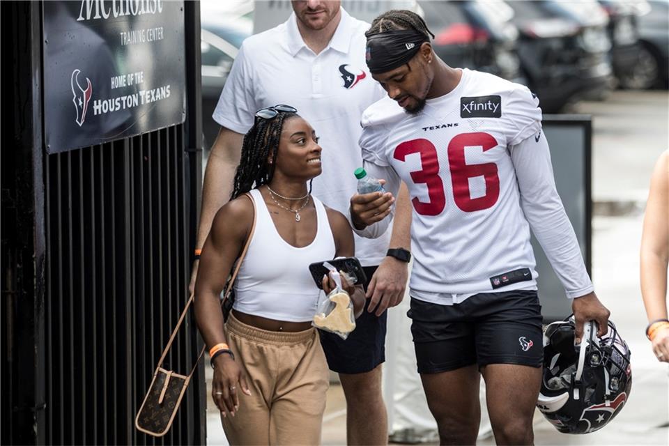 Simone Biles (l) begleitet Freund Jonathan Owens nach einem Training der Houston Texans.