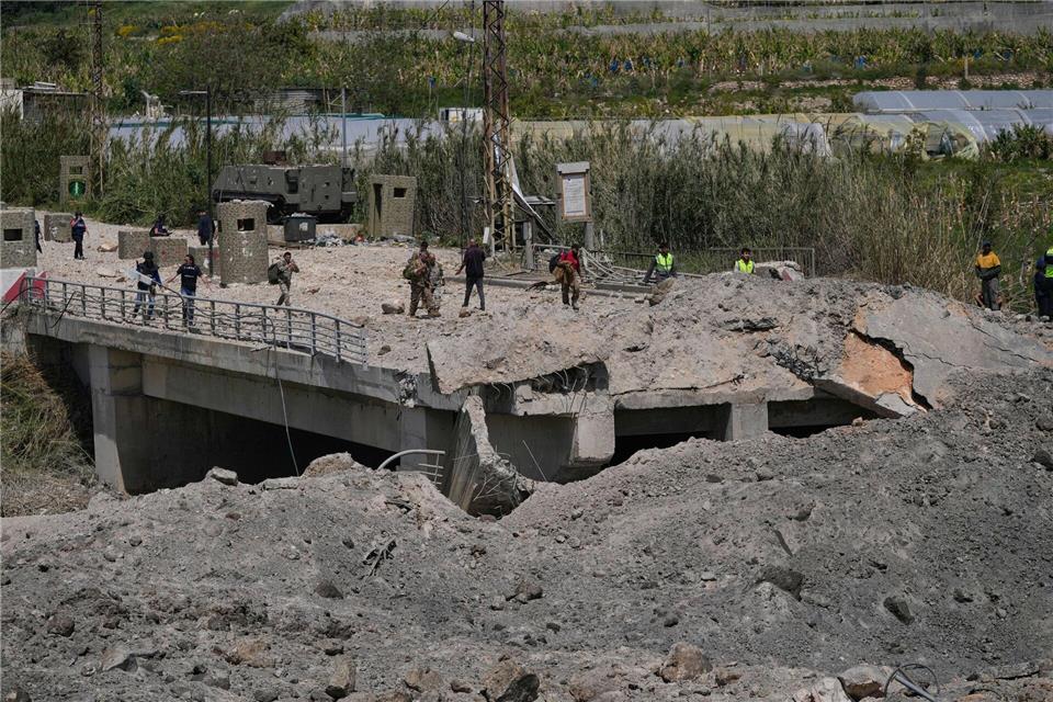 Soldaten und Zivilisten überqueren eine zerstörte Brücke, die bei einem israelischen Luftangriff nahe der Küstenstadt Tyrus im Libanon getroffen wurde.Mohammed Zaatari/AP/dpa
