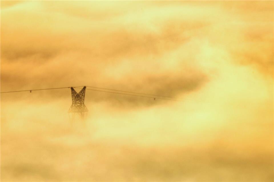 Sonnenaufgang in Riedlingen: Strommastspitze im goldenen NebelThomas Warnack/dpa
