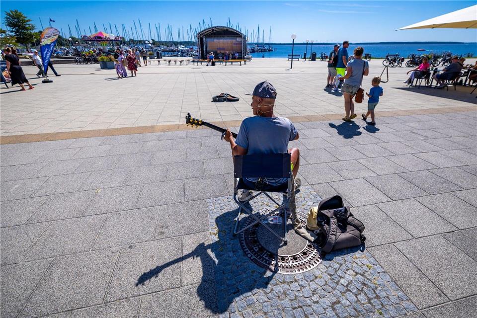 Sonniges Sommerwetter: Straßenmusiker spielt an der Promenade am SalzhaffJens Büttner/dpa