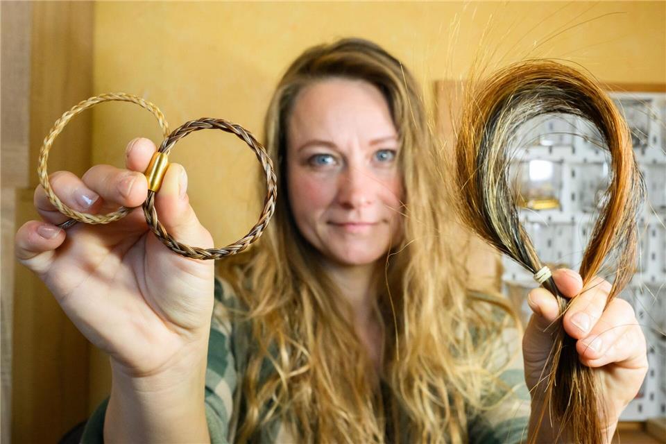 Sophie Dongowski zeigt Pferdehaar und aus solchen Haaren gefertigte Armbänder.Julian Stratenschulte/dpa