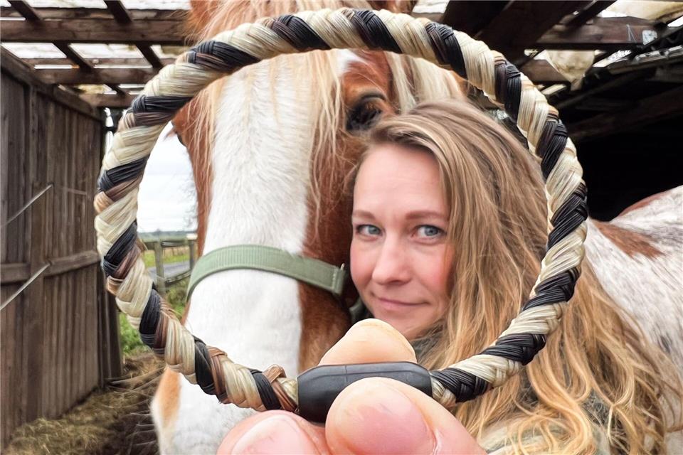 Sophie Dongowski zeigt neben ihrem Pferd Valentino ein aus Pferdehaar und Menschenhaar gefertigtes Armband. Julian Stratenschulte/dpa