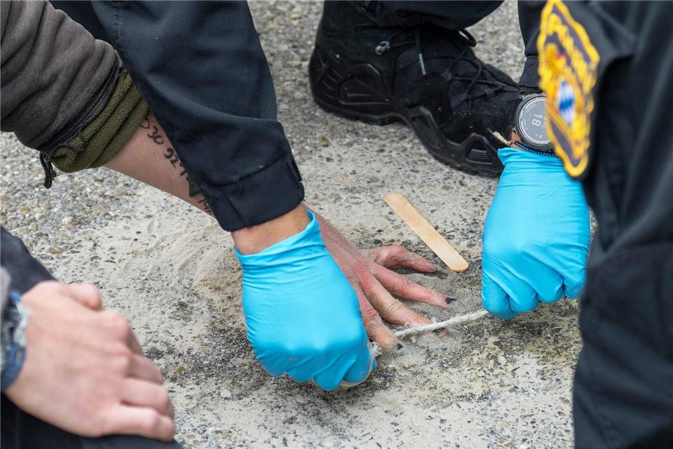 Klebeprotest an Zufahrt zu Rüstungsfirma Renk Speziell geschulte Polizisten versuchten, die Hände von Demonstranten von der Straße zu lösen.Stefan Puchner/dpa
