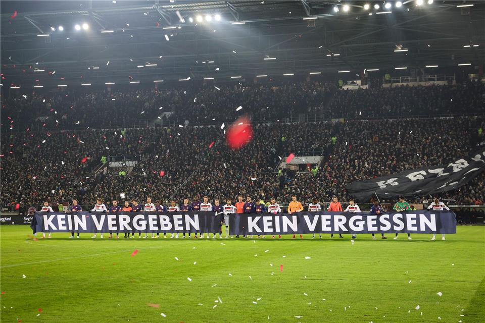 Spieler beider Teams halten vor Spielbeginn ein Banner anlässlich das Holocaust-Gedenktags hoch.Christian Charisius/dpa