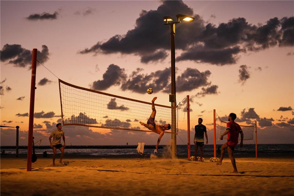 Strandbesucher spielen Fußball und Volleyball am Mittelmeer in Tel Aviv.Francisco Seco/AP/dpa