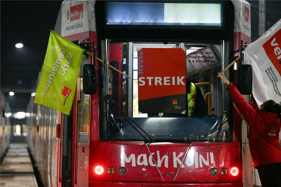 Streikende bringen Verdi-Flaggen an einer Straßenbahn an.