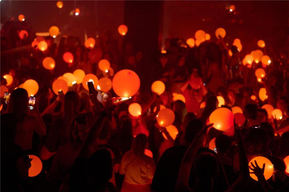 „Swifties“ erleuchten in Bochum auf einer Party der Reihe „Taylor Party Europe“ orangefarbene Luftballons mit den Lichtern ihrer Smartphones.Bernd Thissen/dpa