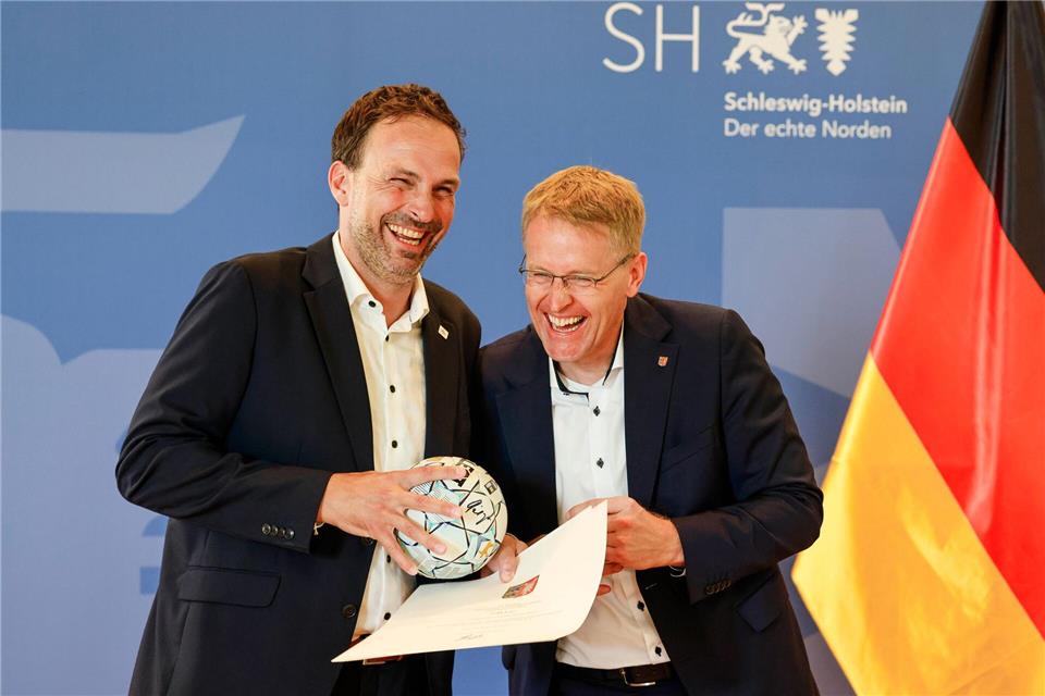 THW-Geschäftsführer Viktor Szilagyi (l) erhielt von Ministerpräsident Daniel Günther einen Handball.Frank Molter/dpa