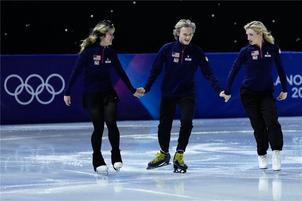Team-Olympiasieger vereint: Ilia Malinin (M) lief Hand in Hand mit Alysa Liu (l), die auch Einzel-Gold holte, und Amber Glenn (r).Ashley Landis/AP/dpa