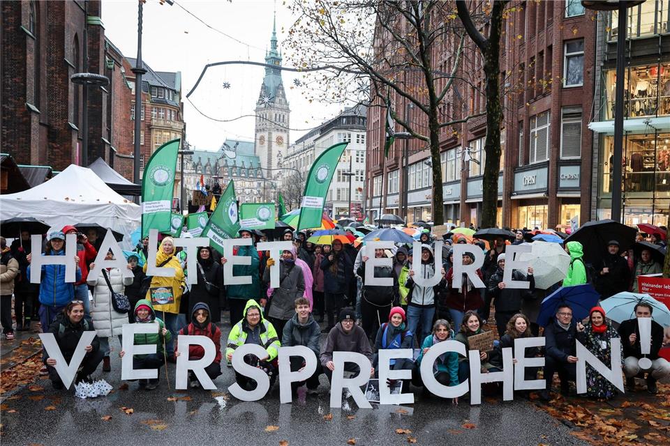 Teilnehmer der Demonstration in Hamburg halten Buchstaben, die einen Slogan ergeben. Christian Charisius/dpa