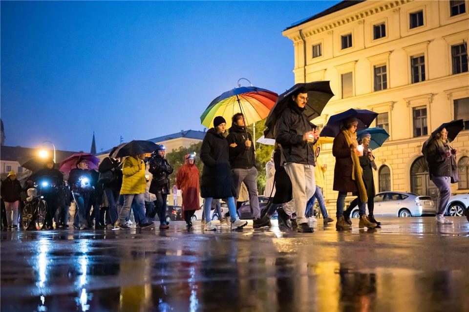 Teilnehmer des Schweigemarschs „Mach Dich auf für Menschlichkeit!“ gehen mit Kerzen auf der Ludwigsstraße in München.Tobias Hase/dpa