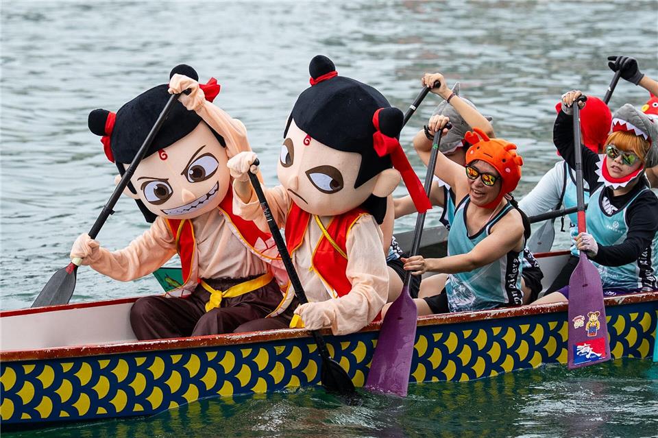 Teilnehmer in bunten Kostümen rudern beim Drachenbootfest in Hongkong.Chan Long Hei/AP/dpa