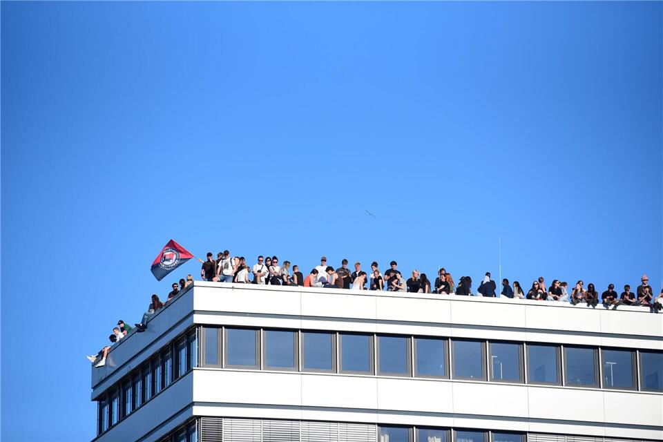 Teilnehmer stehen bei einer Demonstration mit dem Motto „Krieg und Krise haben System. Als Klasse vereint: Sozialismus erkämpfen!“ auf dem Dach eines Hauses in Hamburg.Daniel Bockwoldt/dpa