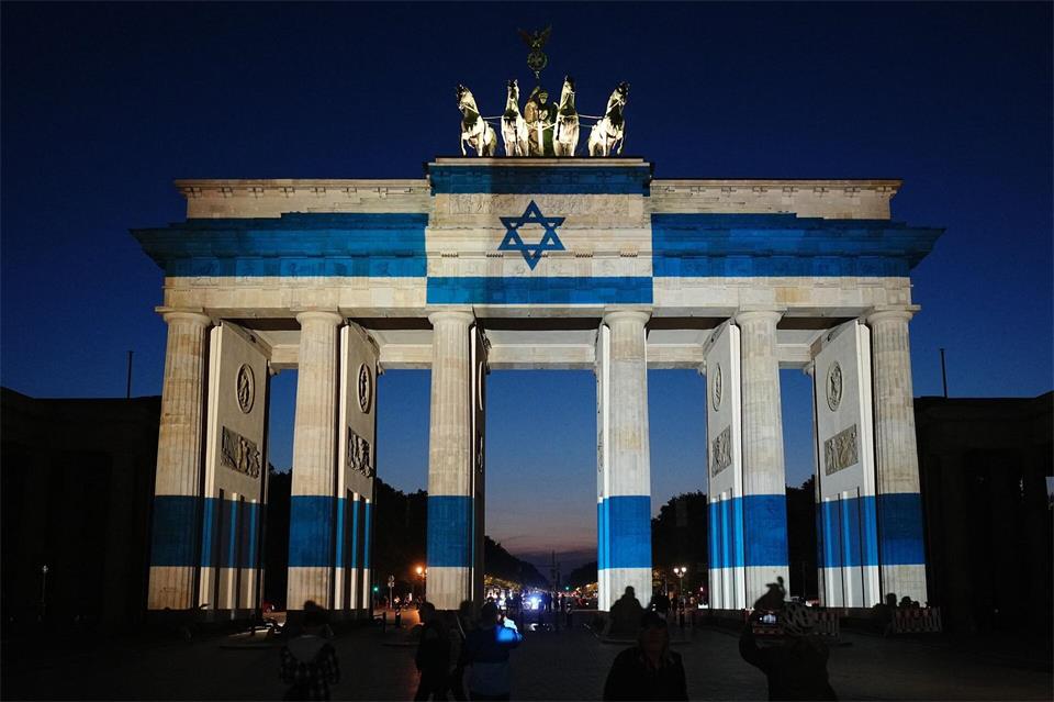 Teilnehmer stehen vor dem mit der Fahne Israels angestrahlten Brandenburger Tor und gedenken bei der Veranstaltung zum Jahrestag des Terrorangriffs der Hamas auf Israel am 7. Oktober 2023 den Opfern.Kay Nietfeld/dpa