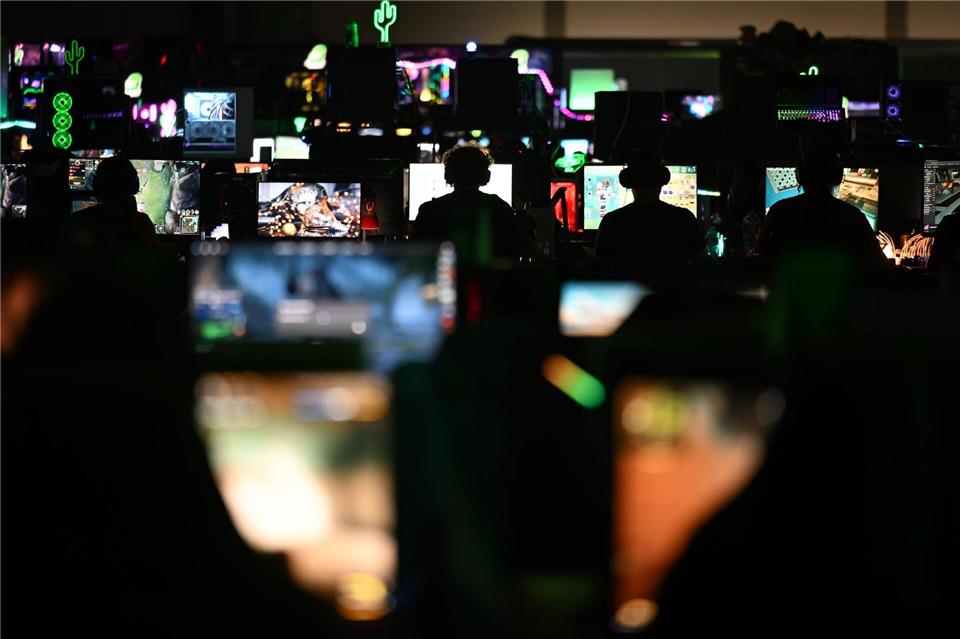 Teilnehmer und Besucher des Gaming-Festivals auf der Messe Leipzig sitzen vor Bildschirmen.Hendrik Schmidt/dpa