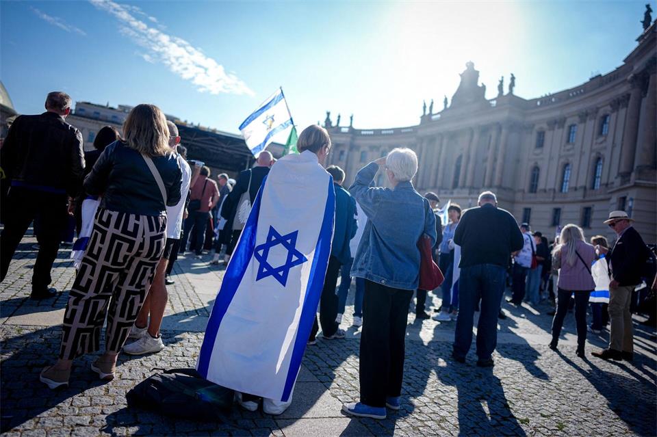 Teilnehmer zeigen die Fahne Israels bei einer Gedenkveranstaltung auf dem Bebelplatz zum Jahrestag des Terrorangriffs. Kay Nietfeld/dpa