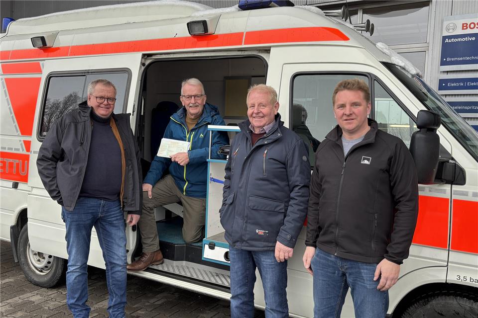 Thomas (rechts) und Hubert Südholt (2. von rechts) sowie Stefan Hülsdünker (links) übergeben den Rettungswagen an Ludger Jacobs (kniend).