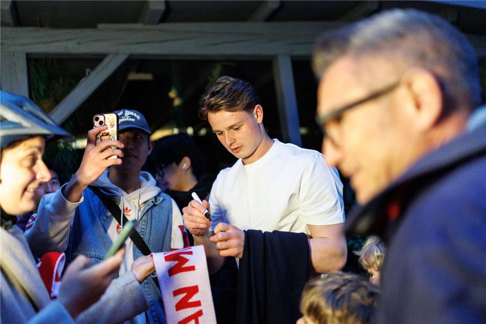 Torhüter Jonas Urbig schreibt Autogramme, bevor er mit seinen Teamkollegen feiert. Matthias Balk/dpa