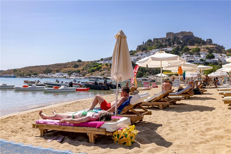 Rhodos kämpft gegen das Feuer - und bangt um Tourismuus Touristen am Strand von Lindos auf Rhodos etwa 10 Kilometer von den Bränden im Südosten entfernt.