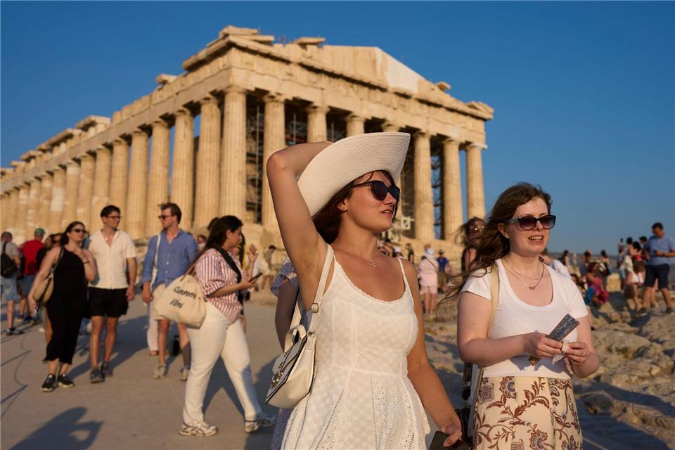 Touristen gehen an einem heißen Tag am antiken Parthenon-Tempel auf dem Akropolis-Hügel vorbei.Petros Giannakouris/AP/dpa