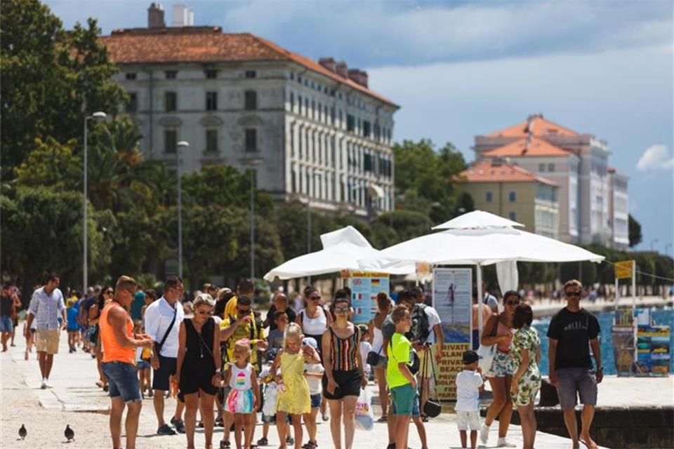 Touristen spazieren an der Uferpromenade in Zadar, Kroatien entlang. Die kroatische Tourismusbranche fürchtet eine weitreichende Reisewarnung der Bundesregierung. Foto: Marko Dimic/Pixsell/Xinhua/dpa