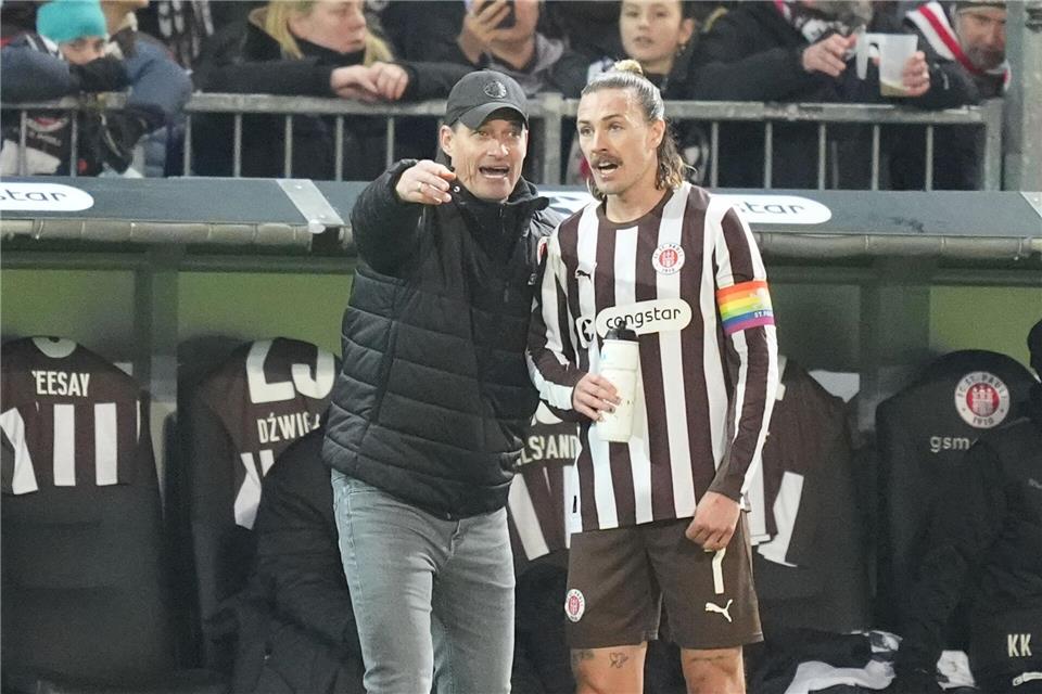 Trainer Alexander Blessin spricht mit St.-Pauli-Kapitän Jackson Irvine.Marcus Brandt/dpa