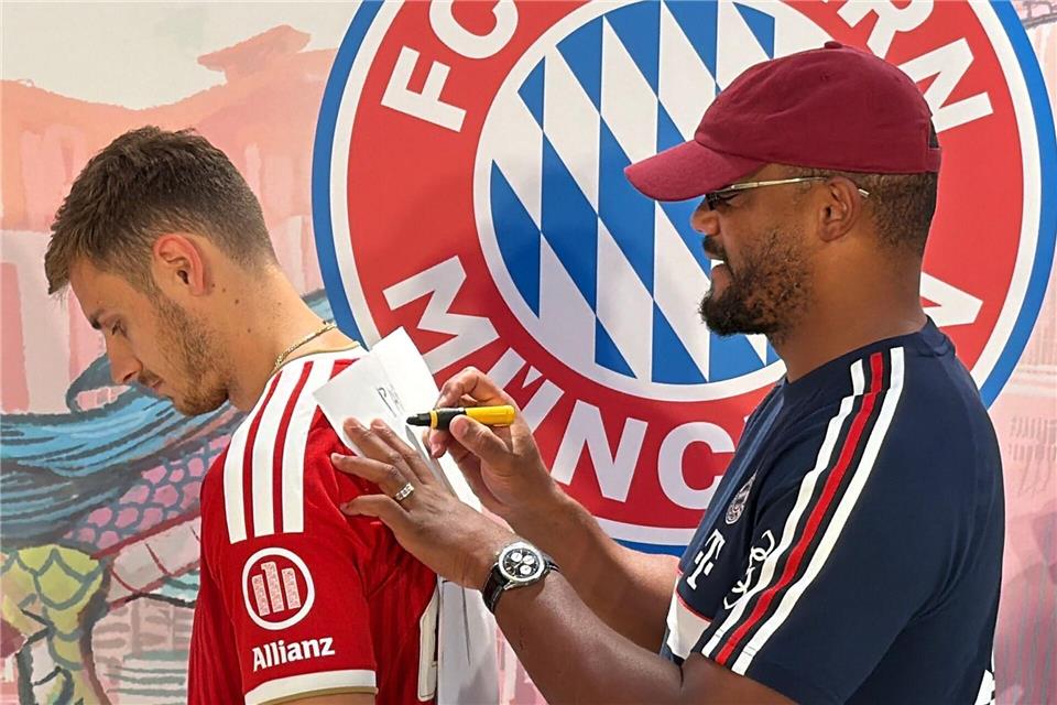 Trainer Vincent Kompany (r) malt - und Josip Stanisic muss raten. Christian Kunz/dpa