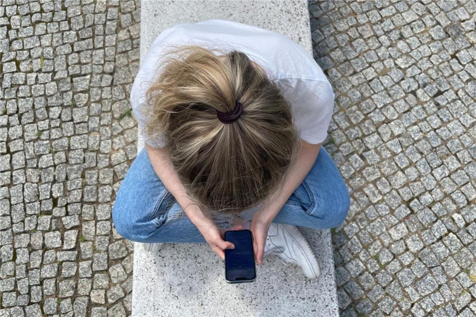 Typische Haltung in heutiger Zeit: mit gesenktem Kopf auf das Handy schauen.Ricarda Dieckmann/dpa-tmn