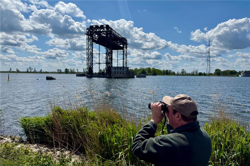 Ulf Wigger hält Ausschau nach Seeadlern - im Hintergrund: die historische Hubbrücke Karnin.Wolfgang Stelljes/dpa-tmn