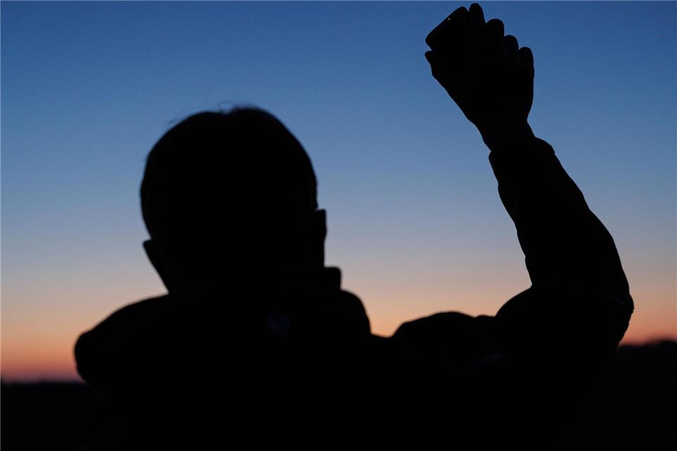 Umweltwissenschaftler Marcel Holy hält einen Lautsprecher in die Höhe. Der aufgezeichnete Revierruf des männlichen Rebhuhnes soll die echten Hähne dazu bringen, lautstark zu antworten. So können die Wildvögel gezählt werden. David Ebener/dpa