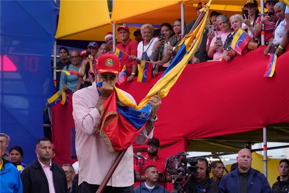 Venezuelas Präsident Nicolas Maduro küsst eine venezolanische Flagge während einer Veranstaltung im Präsidentenpalast in Caracas.Ariana Cubillos/AP/dpa