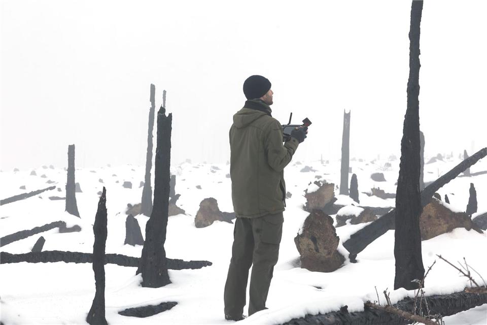 Verkohlte Baumreste künden noch vom großen Waldbrand auf der Saalfelder Höhe, auf der eine Drohne Baumsaat zur Wiederaufforstung aufbringt.Bodo Schackow/dpa