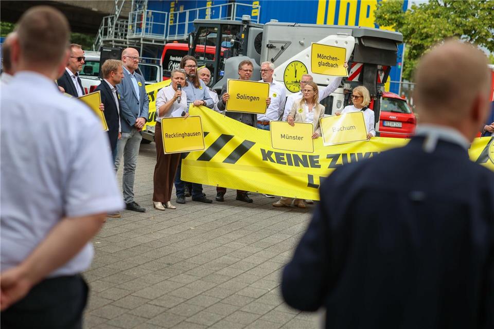 Vertreter mehrerer Städte und Kommunen in NRW halten Schilder und Banner bei einer Kundgebung vor der Abfahrt nach Berlin.Christoph Reichwein/dpa