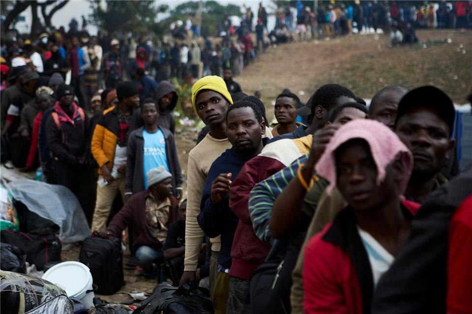 Vertriebene Migranten stehen in Durban in Südafrika vor einer Abschiebeeinrichtung Schlange.Uncredited/AP/dpa