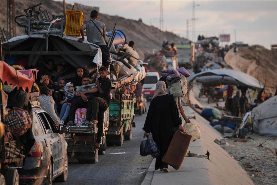 Vertriebene Palästinenser, die aus dem nördlichen Gazastreifen fliehen, tragen ihre Habseligkeiten entlang der Küstenstraße in Richtung des südlichen Gazastreifens.Jehad Alshrafi/AP/dpa