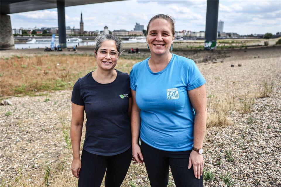 Victoria Blocksdorf (r) von der Initiative Blockblocks Cleanup und Miriam Schenke (l), Geschäftsführerin von Rhein Cleanup, stehen am Rheinufer in Düsseldorf. Oliver Berg/dpa