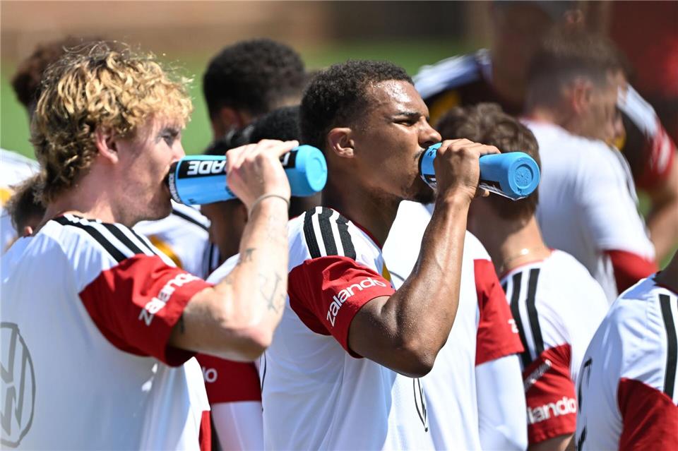 Viel Trinken gegen die Hitze, Nick Woltemade (l) und Malick Thiaw in einer kurzen Trainingspause. Federico Gambarini/dpa