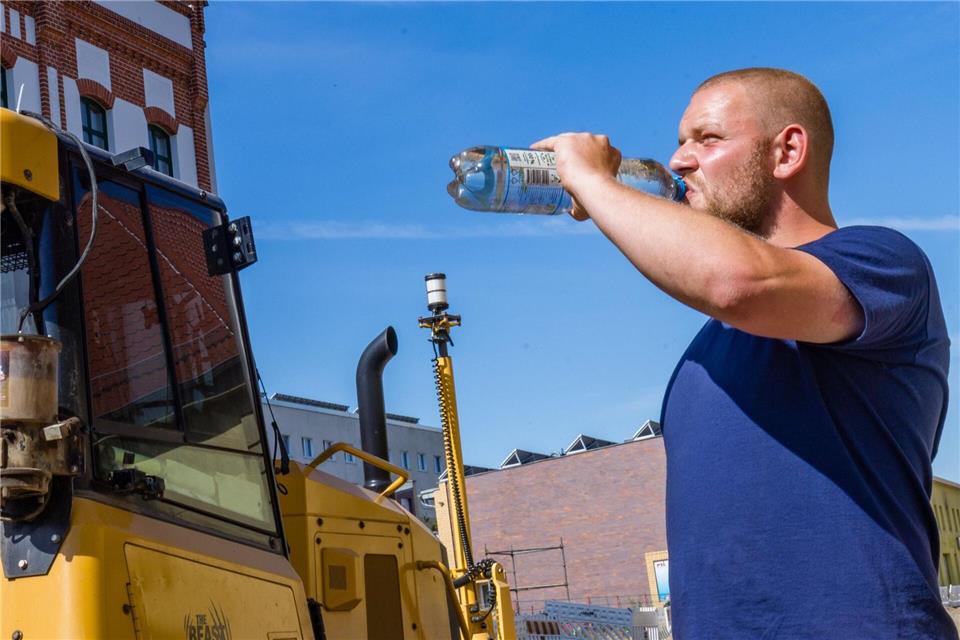 Viel Trinken ist bei Hitze besonders wichtig, weiß auch dieser Arbeiter auf einer Baustelle in Cottbus.Frank Hammerschmidt/dpa