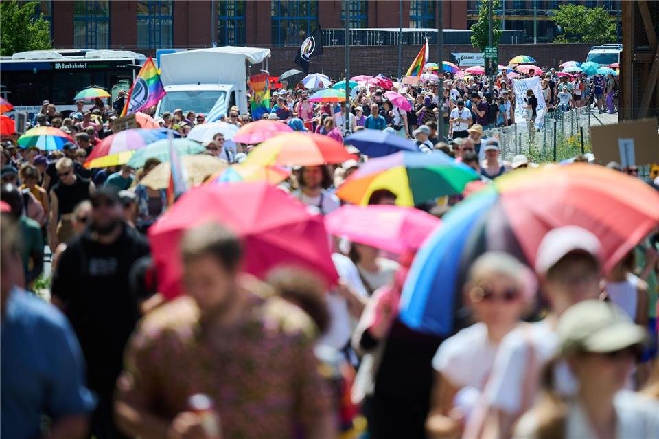 Viele Menschen in der Parade haben bunte Schirme dabei.Annette Riedl/dpa