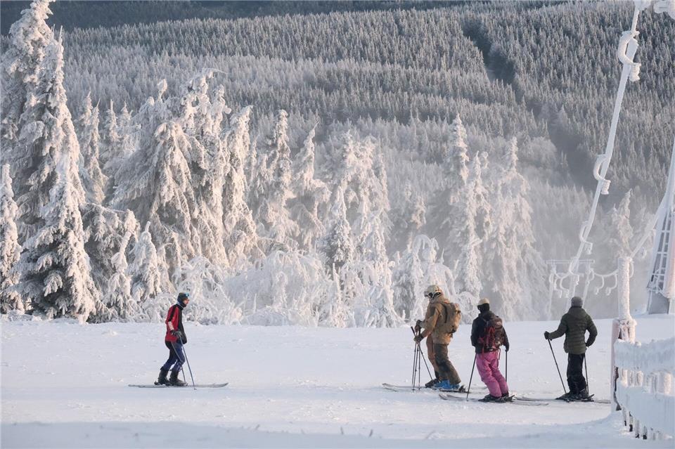 Vor winterlicher Kulisse schnallen sich vereinzelt Wintersportler auf dem Fichtelberg ihre Skier an. Die Pisten von Sachsens größtem alpinen Skigebiet sind derzeit aber noch geschlossen. Sebastian Willnow/dpa