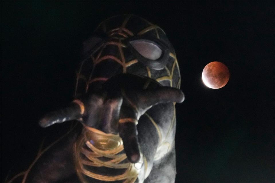 Während der partiellen Mondfinsternis geht in El Alto, Bolivien, der Mond hinter einer Spider-Man-Statue auf.Juan Karita/AP/dpa