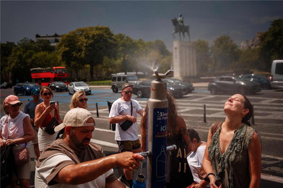Während einer Hitzewelle in Paris suchen Menschen an einem Nebelbrunnen auf der Place du Trocadéro Abkühlung.Dimitar Dilkoff/AFP/dpa